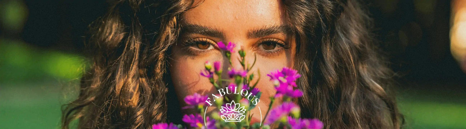 Woman with curly hair holding a bouquet of purple flowers close to her face - Fabulous Flowers and gifts