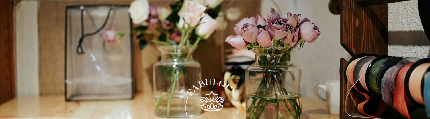 Roses and proteas elegantly arranged in glass vases on a well-organised florist's workbench