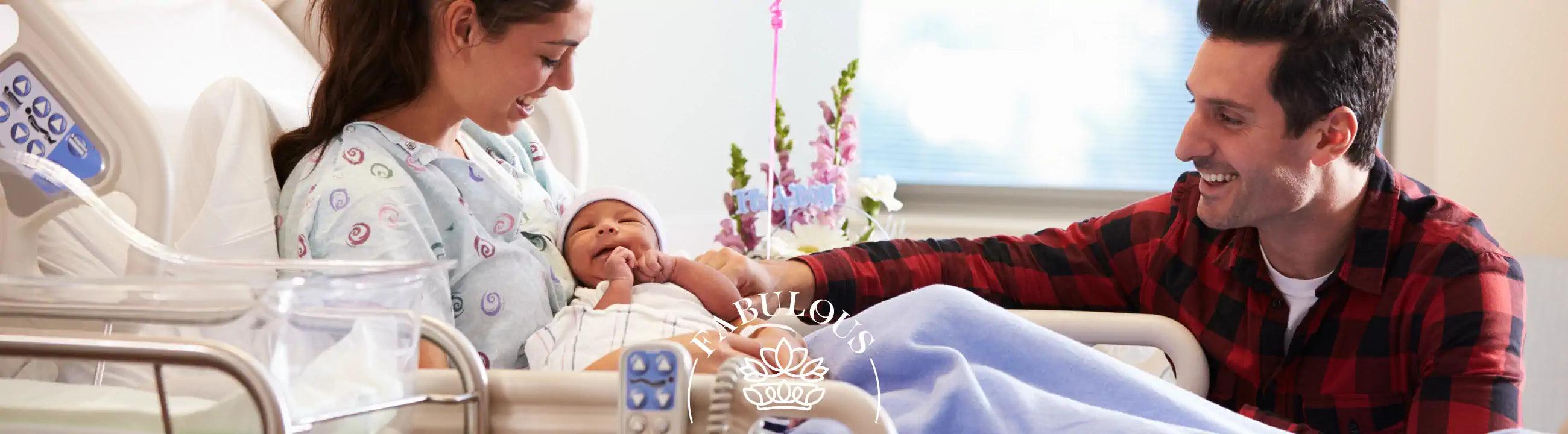 "Happy new parents in a hospital room, mother holding newborn baby while father looks on smiling.