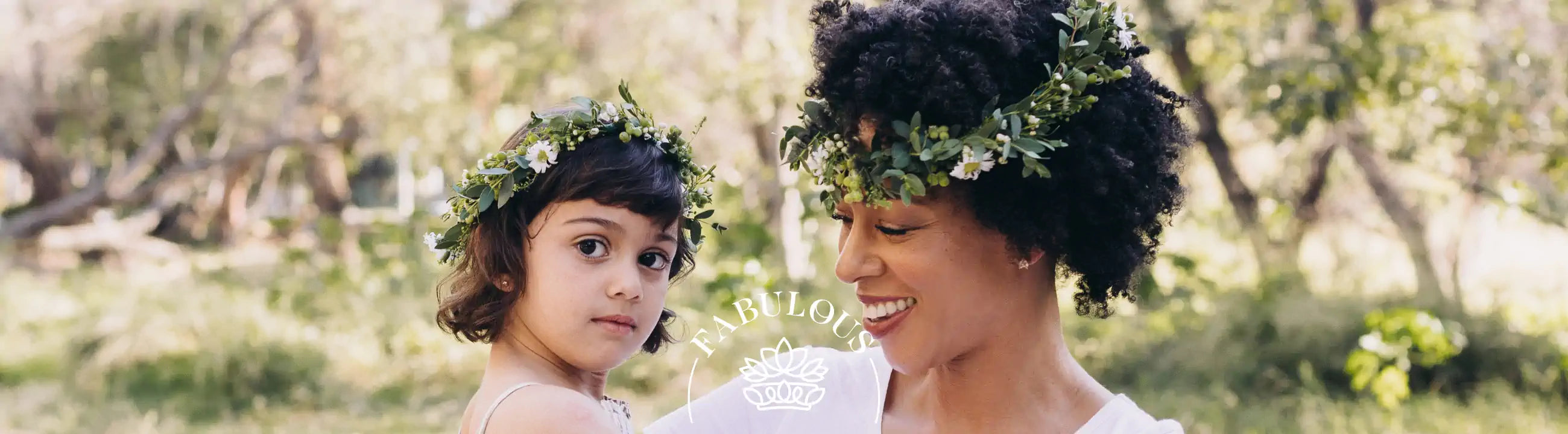 A mother and daughter wearing flower crowns and sharing a joyful moment in a lush garden. Fabulous Flowers and Gifts.