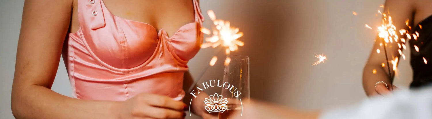 Close-up of two women in elegant dresses holding sparklers and a champagne glass. Fabulous Flowers and Gifts.