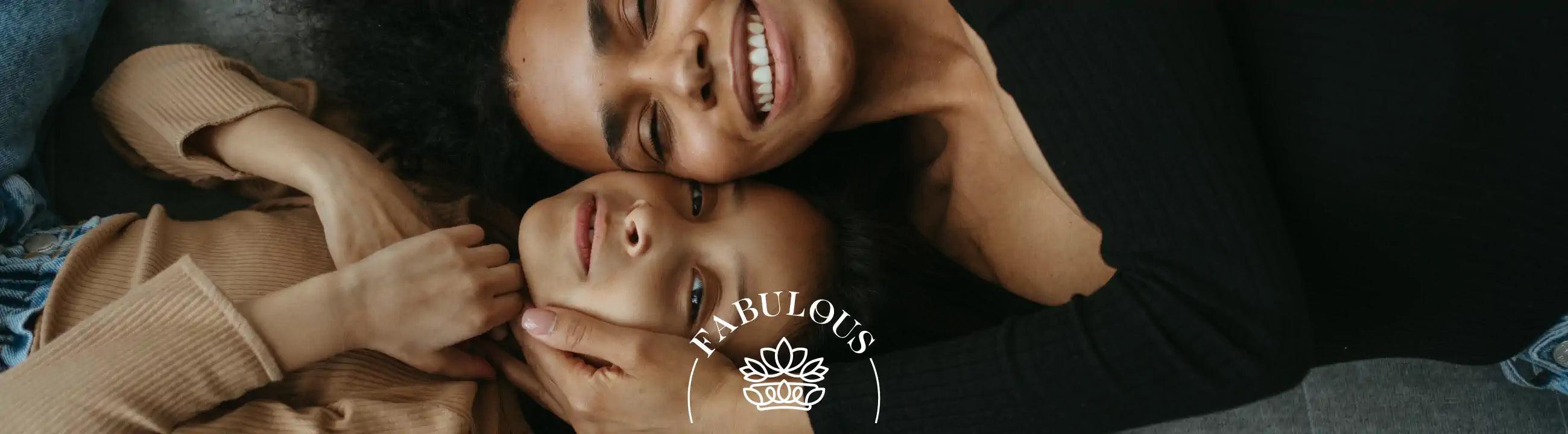 A mother and daughter lying close together, smiling warmly with their heads touching. Fabulous Flowers and Gifts.