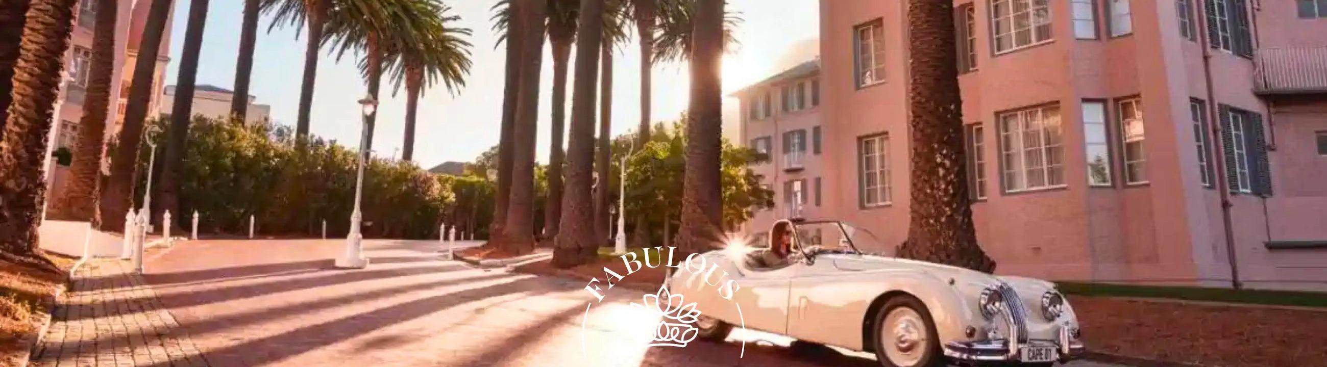  A woman driving a classic white convertible along a palm-lined street, with elegant buildings bathed in sunlight. Fabulous Flowers and Gifts.