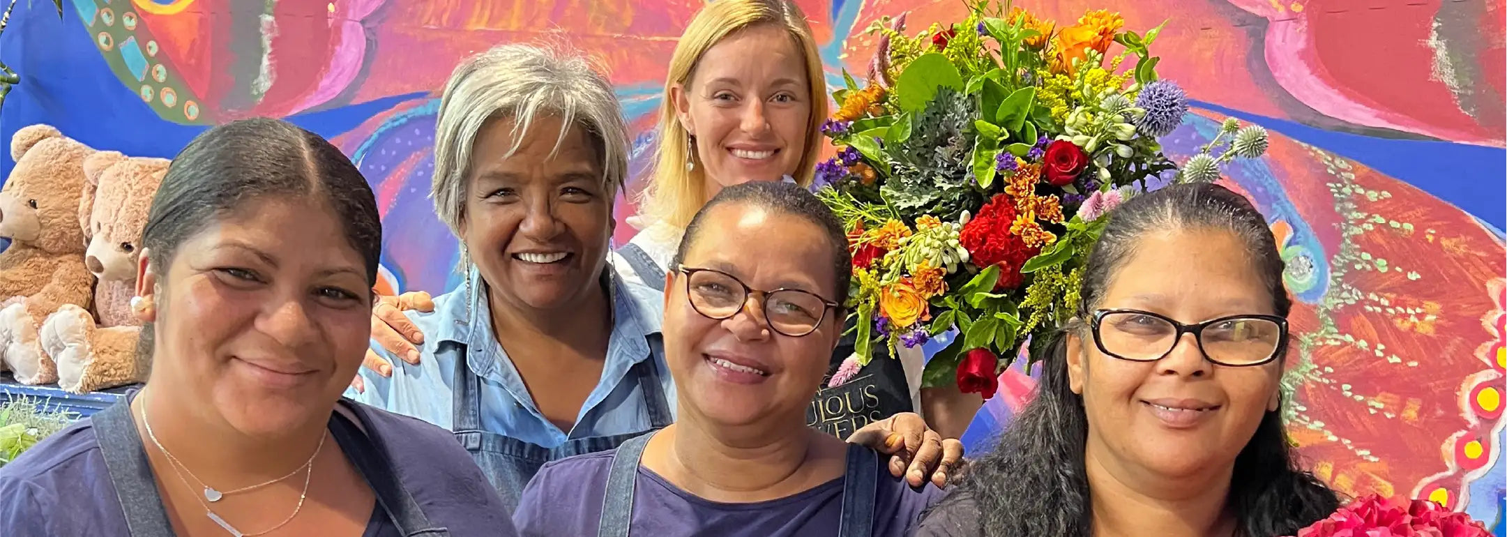 Fabulous Flowers team members smiling in front of a colourful backdrop, showcasing their dedication to creating spectacular floral arrangements. Fabulous Flowers and Gifts.