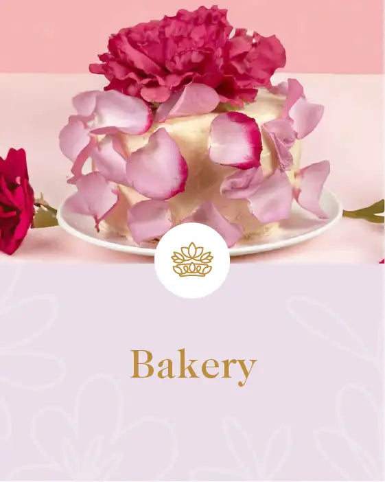 Elegant cake adorned with pink and red rose petals and large flower on top, displayed on a white plate. Fabulous Flowers and Gifts. Bakery Collection.
