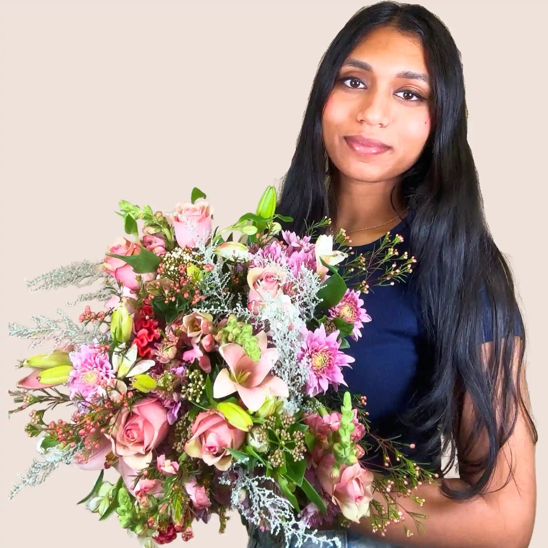 A smiling woman holding a stunning bouquet of mixed pink and white flowers, featuring roses, lilies, and assorted greenery. Bella’s Flower Bouquet. Fabulous Flowers and Gifts.