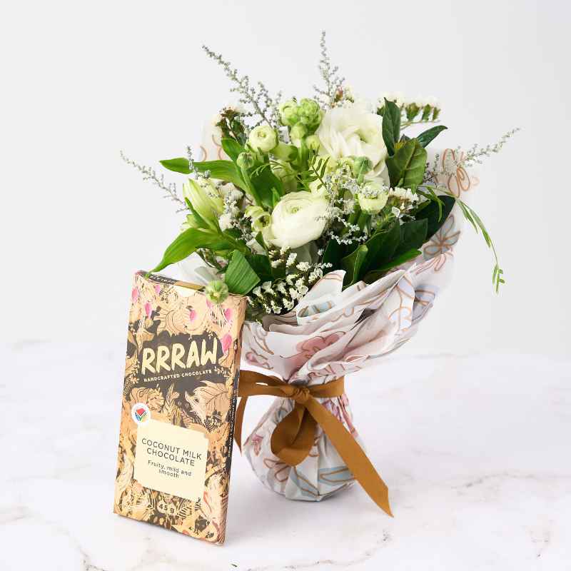 Bloom Boutique Posy - A delicate posy of white and green flowers wrapped in floral paper, accompanied by a Rrraw handcrafted coconut milk chocolate bar.