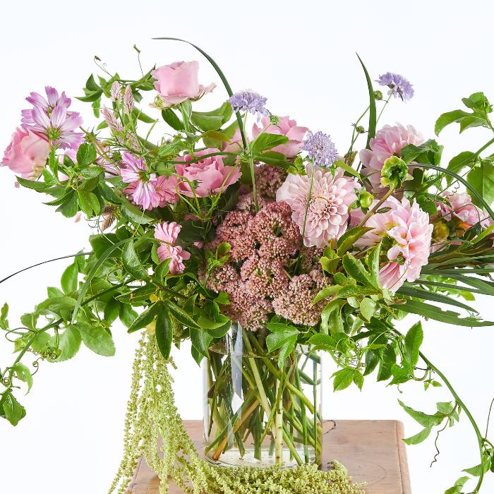 Elegant Bloom Blush flower arrangement with pink and green botanicals in a transparent vase.