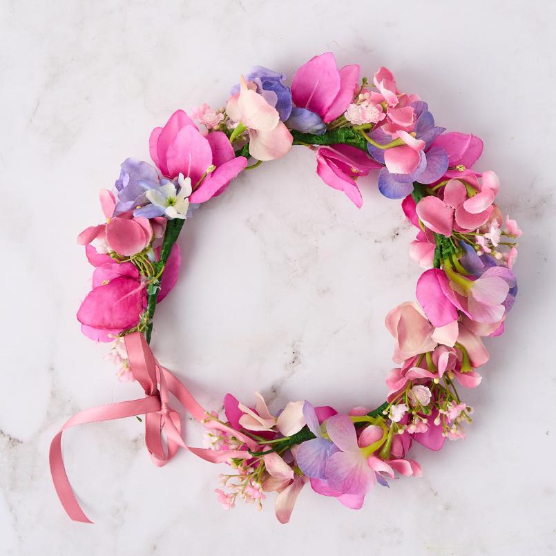 Pink and purple floral crown with delicate blooms and a pink ribbon tie.