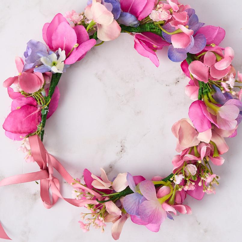 Close-up of pink and purple flower crown featuring pastel petals and pink ribbon.