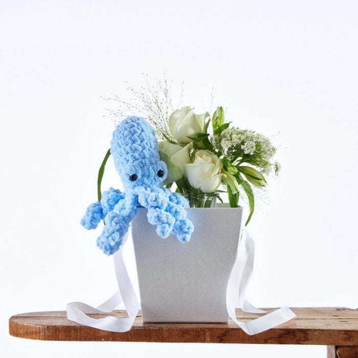 Blue Reef Blossom Bag featuring a crochet blue octopus and elegant white rose arrangement in a stylish gift bag.