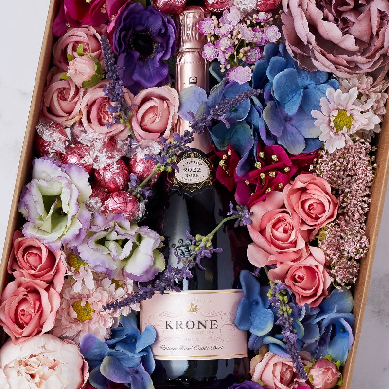 Close-up of Krone Rosé bottle in an elegant floral arrangement with Lindt chocolates for a special celebration