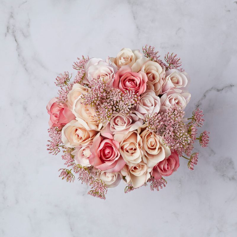 Top view of artificial blush and cream rose bouquet with pink filler flowers, arranged elegantly.