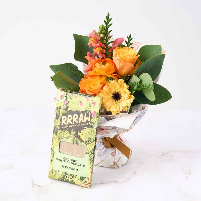 Botanical Beauty Posy - A vibrant posy of orange and yellow flowers wrapped in floral paper, paired with a Rrraw handcrafted coconut white chocolate bar.