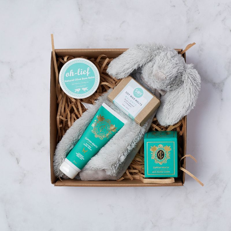 Gift box with Oh-Lief natural bum balm, Clifton Beach hand lotion, soy wax melts, mini candle, and grey plush bunny.