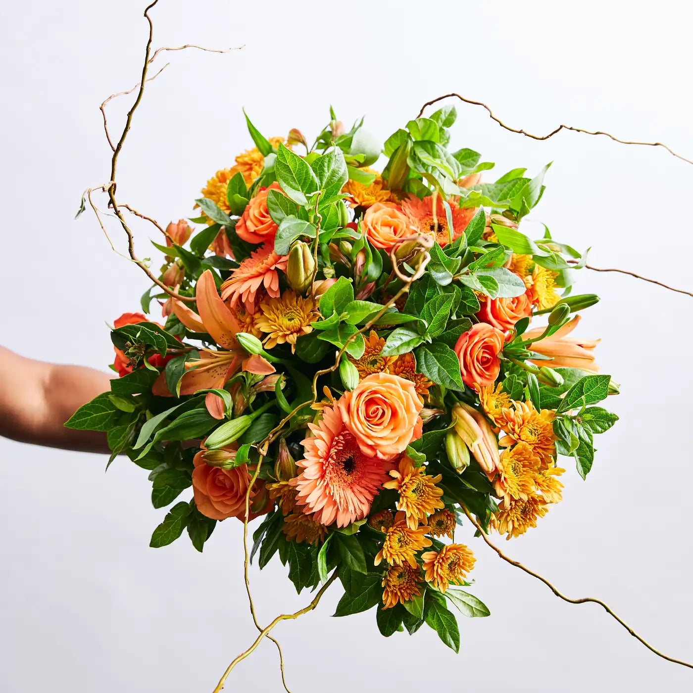 A hand holding a bouquet of vibrant orange and green flowers, symbolising the artistry and dedication of Fabulous Flowers and Gifts. Our Story.