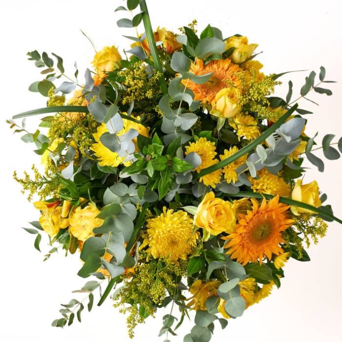 Top-down view of the Buttercup Brilliance bouquet, showcasing bright yellow flowers, fresh eucalyptus, and sun-kissed floral textures.