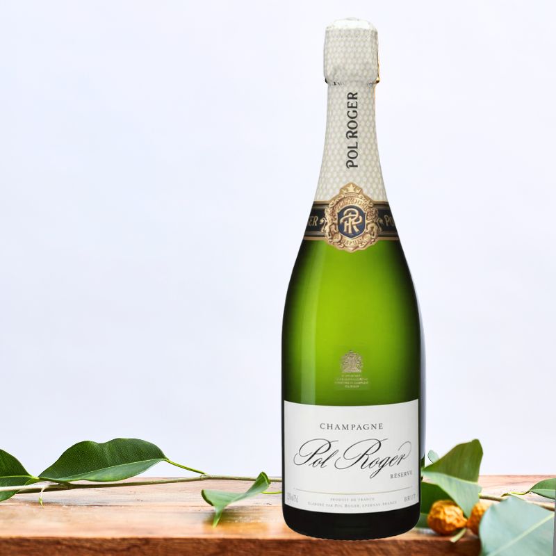 Champagne Pol Roger Reserve bottle with a classic white and gold label, elegantly displayed on a wooden table with green leaves.