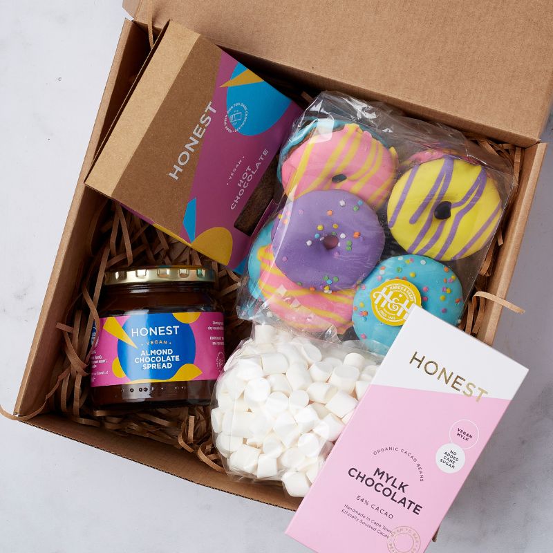 Top view of a vegan gift box with almond chocolate spread, colorful donuts, mini marshmallows, and Honest Mylk Chocolate.