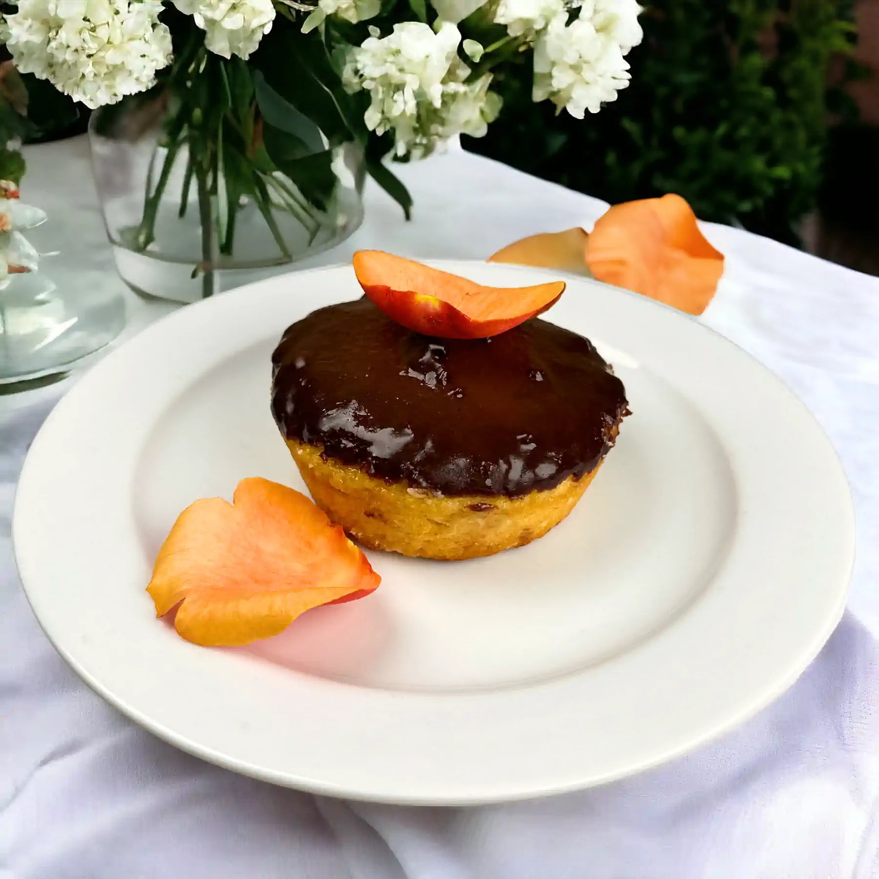 Decadent chocolate orange cake topped with chocolate glaze and orange petals, on a white plate. Fabulous Flowers and Gifts.