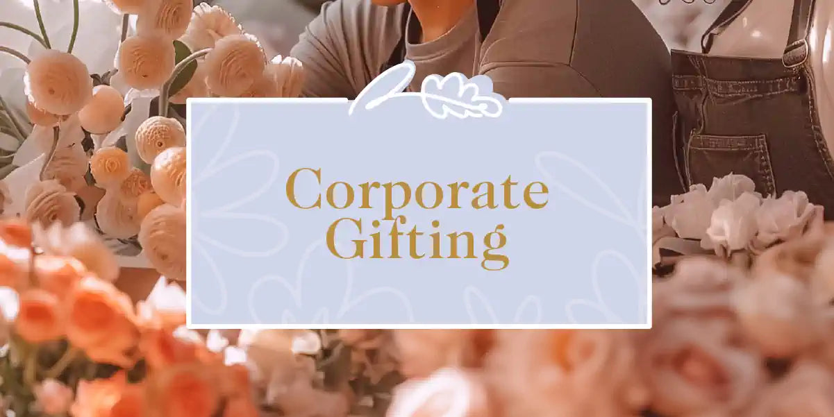 Corporate Gifting Collection: A close-up of a person arranging various elegant flowers in a workspace, showcasing white, cream, and peach blooms. Fabulous Flowers and Gifts.