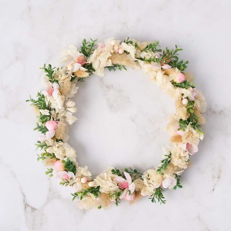 Floral wreath with soft pink and cream flowers on a light background