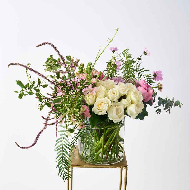 Side view of Creative Poetry Flower Arrangement with white roses and pink flowers in a glass vase.