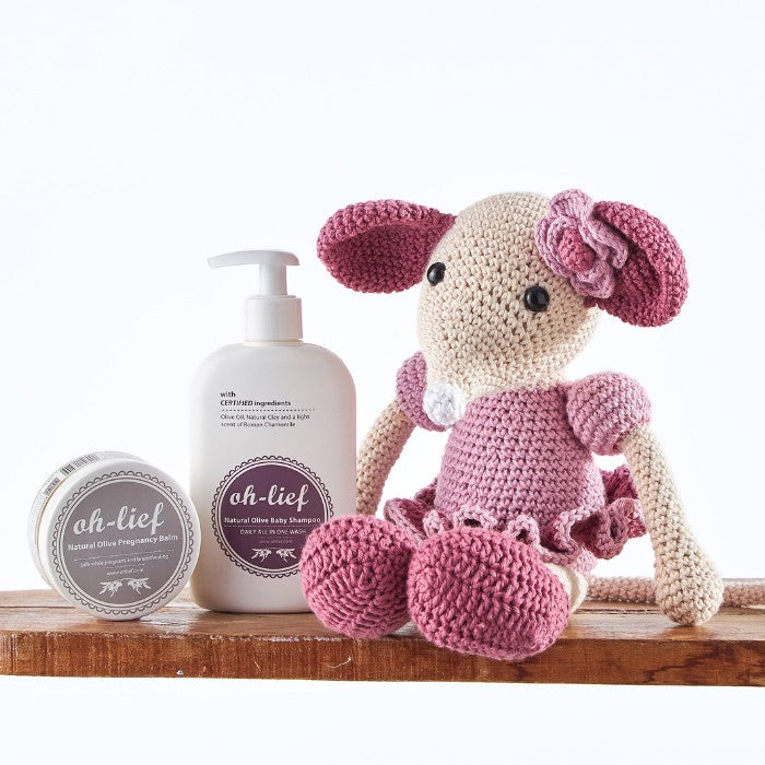 Handcrafted pink crochet mouse with eco-friendly baby care products, including natural shampoo and pregnancy balm.