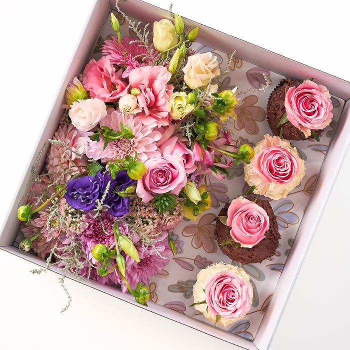 Cupcake Bloom Box by Fabulous Flowers & Gifts, showcasing vibrant pink roses, pastel dahlias, and assorted blooms with pink rose icing on chocolate cupcakes.