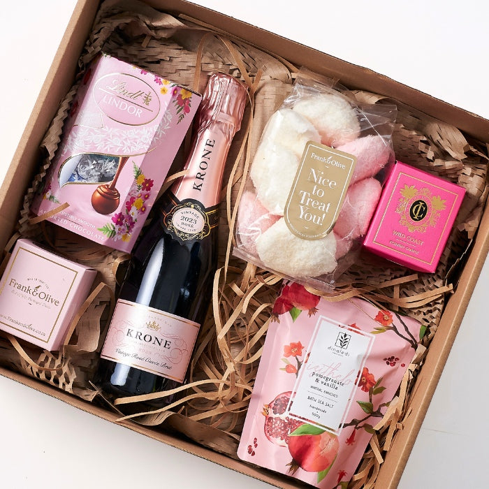 Close-up view of the Daydream Delight gift set displaying assorted luxury items including pink champagne, gourmet sweets, and skincare products in a beautifully presented gift box.