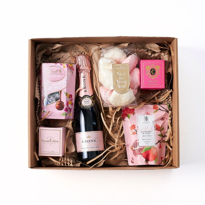 Daydream Delight gift box featuring Krone rose wine, Lindt chocolates, scented candles, and bath salts, artfully arranged in a rustic box.