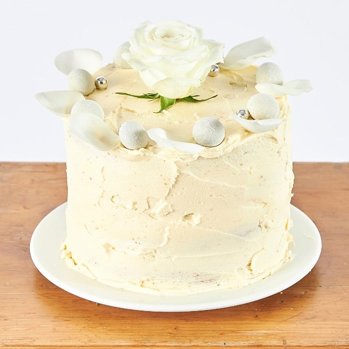 Close-up of an Elegant Rose Celebration Cake with intricate white floral decorations and edible silver accents, perfect for weddings or sophisticated celebrations.