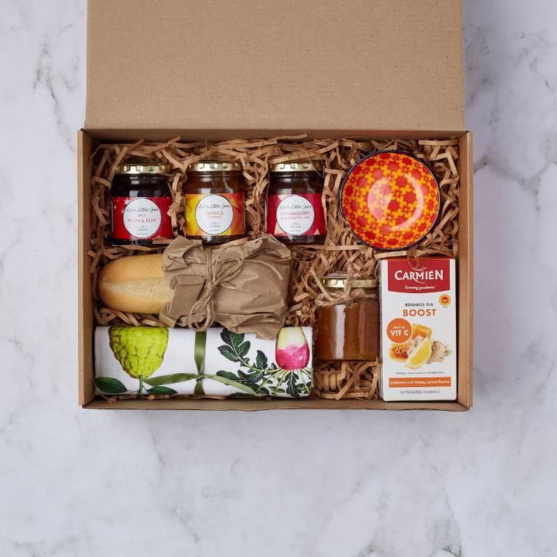 Family Breakfast Gift Box with jams, bread roll, honey, tea, colourful bowl, and napkin arranged in a box.