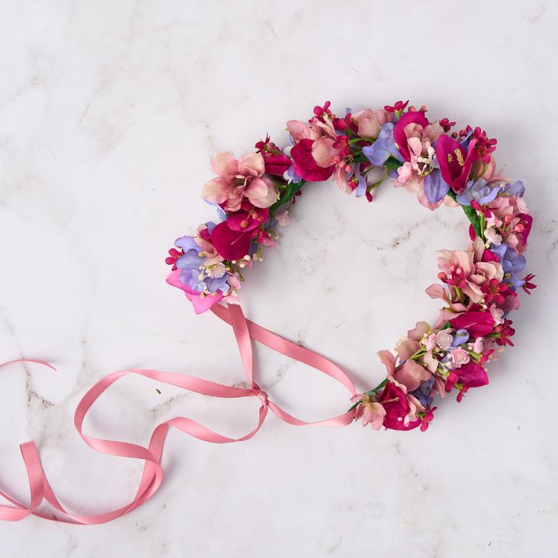 Pink and purple floral crown with vibrant blooms and a pink ribbon tie.