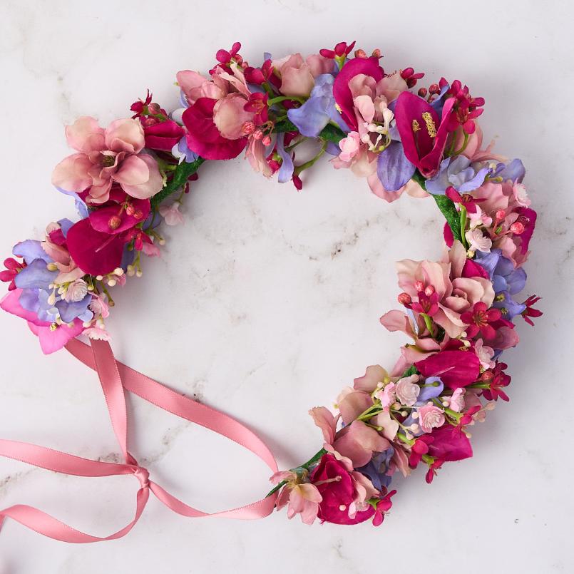 Close-up of pink and purple flower crown featuring delicate petals and a pink ribbon detail.