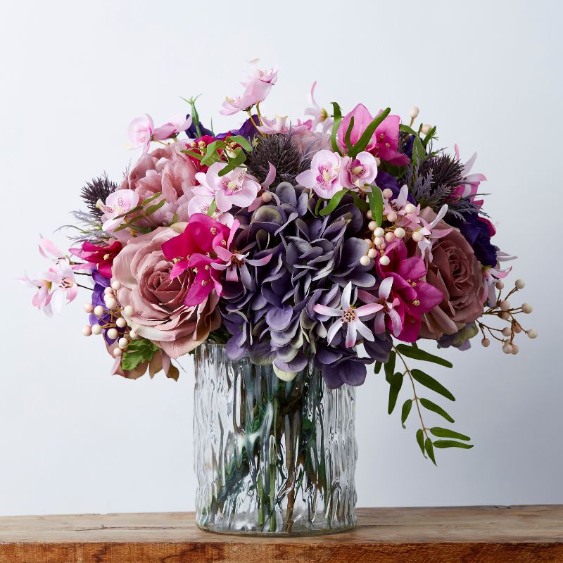 Floral Pop Silk Arrangement with a vibrant mix of pink, purple, and mauve silk flowers in a textured glass vase, showcasing intricate flower details and rich hues for elegant home decor.