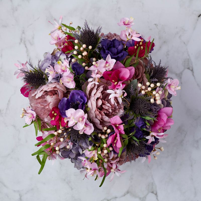 Top view of the Floral Pop Silk Arrangement featuring a vibrant mix of pink, purple, and mauve silk flowers with realistic greenery and berries, arranged in a circular, full-bodied bouquet.