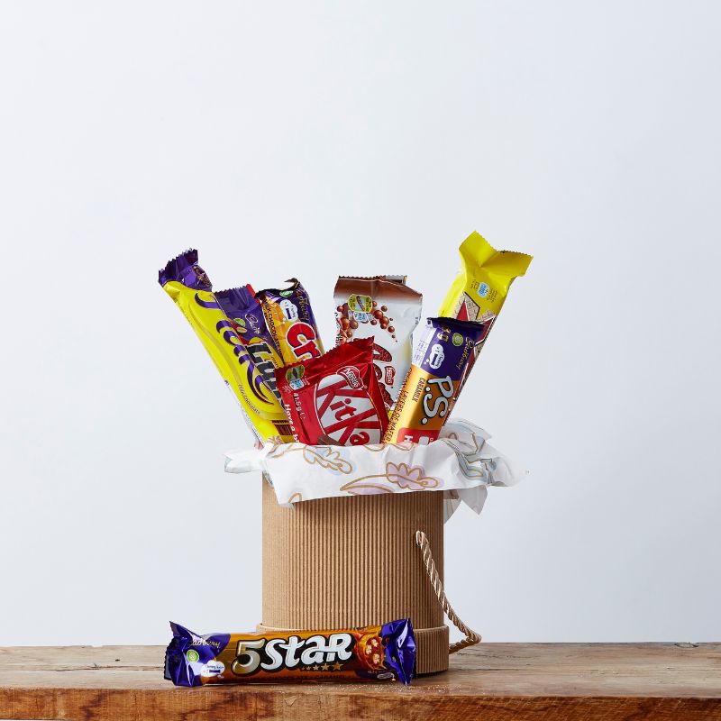 Assortment of popular chocolate bars displayed in a decorative gift box, featuring Cadbury, KitKat, PS., and 5 Star bars.