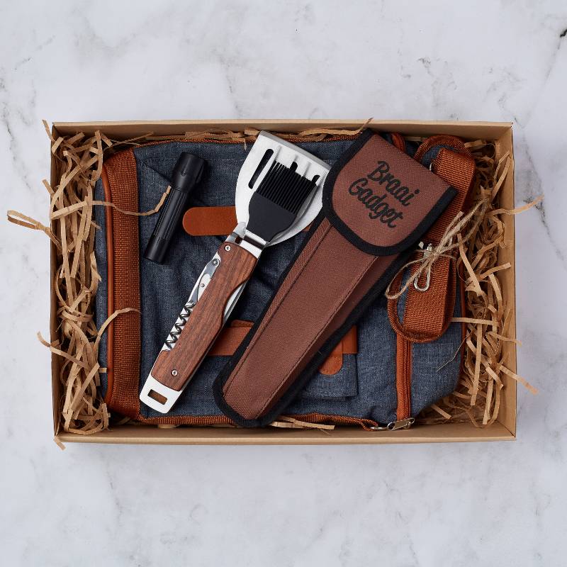 Gadget Dad gift box featuring a multi-tool for braai, flashlight, and denim apron with brown leather straps.