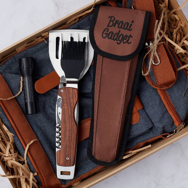 Close-up of the Gadget Dad gift box, highlighting the braai multi-tool, apron, and black flashlight.