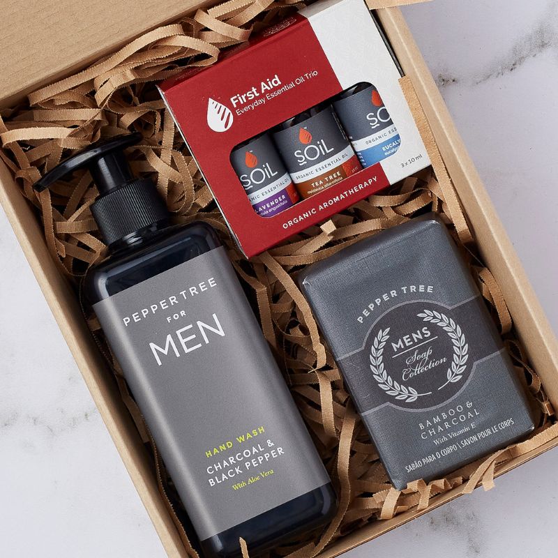 Men’s grooming gift box with Peppertree hand wash, charcoal soap, and SOiL essential oils on crinkle paper