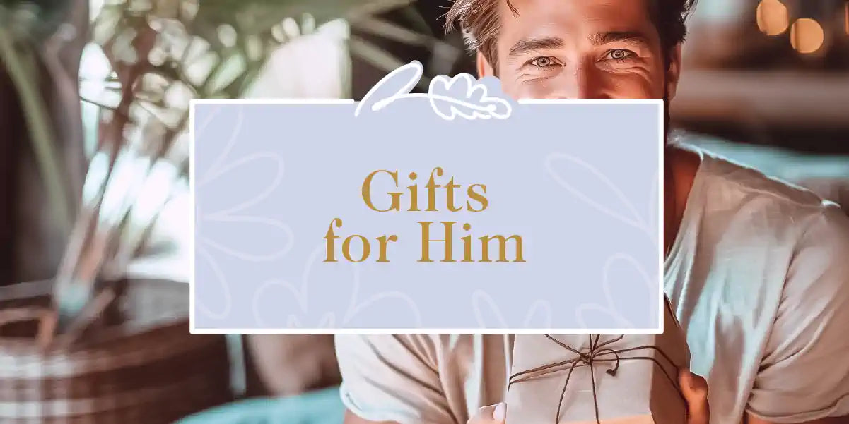 A man with a beaming smile, holding a gift box, set against a cozy and inviting background. Fabulous Flowers and Gifts - Gifts for Him
