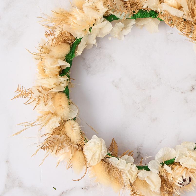 Close-up of dried beige flower crown featuring light ferns and neutral-toned petals.