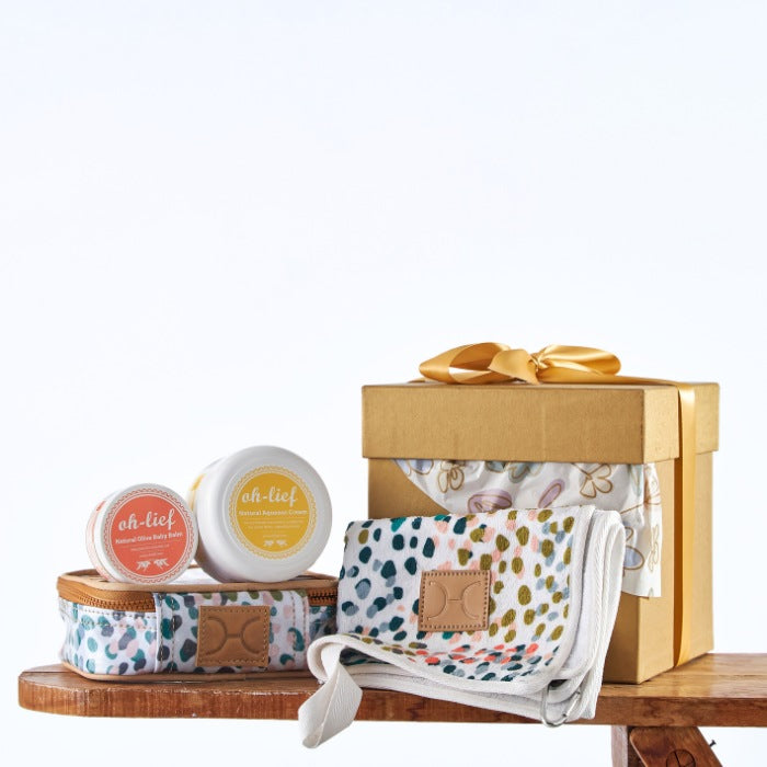 Golden Wishes Baby Care Kit featuring natural skincare products in a golden gift box with a vibrant baby wrap and a ribbon.