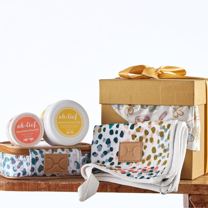 Elegant baby care set in a golden box with natural olive balm, aqua cream, and a colorful patterned baby wrap.