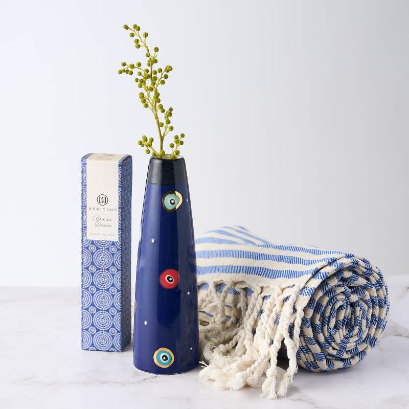 Greek Island Gift featuring a blue evil eye vase, striped Turkish towel, and heritage room spray. A perfect Mediterranean-inspired gift set.