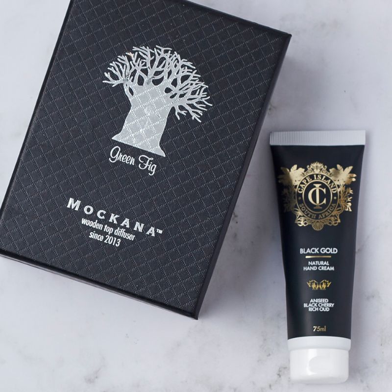 Close-up of Mockana green fig diffuser box and Cape Island Black Gold hand cream with aniseed, black cherry, and rich oud.