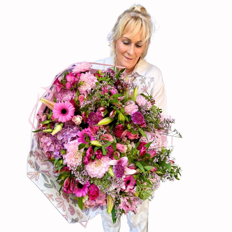 Elegant Handle with Love Bouquet showcasing a blend of pink blooms and delicate foliage, displayed with artistic geometric wrapping paper with floral design.