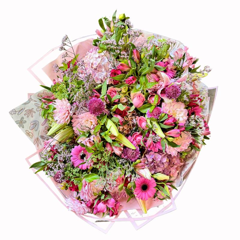 Overhead view of Handle with Love Bouquet revealing intricate floral composition with layers of pink gerberas, dahlias, roses and wispy foliage in geometric wrap.