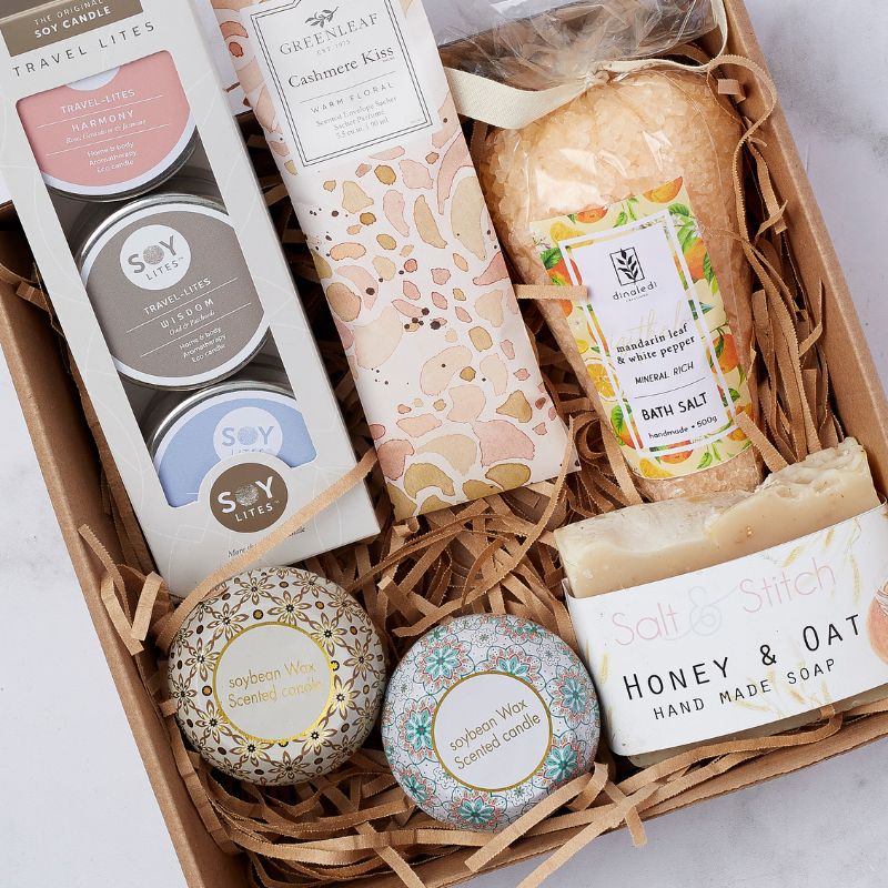 Gift box with soy candles, Cashmere Kiss sachet, mandarin leaf bath salt, and honey oat soap in eco-friendly packaging.